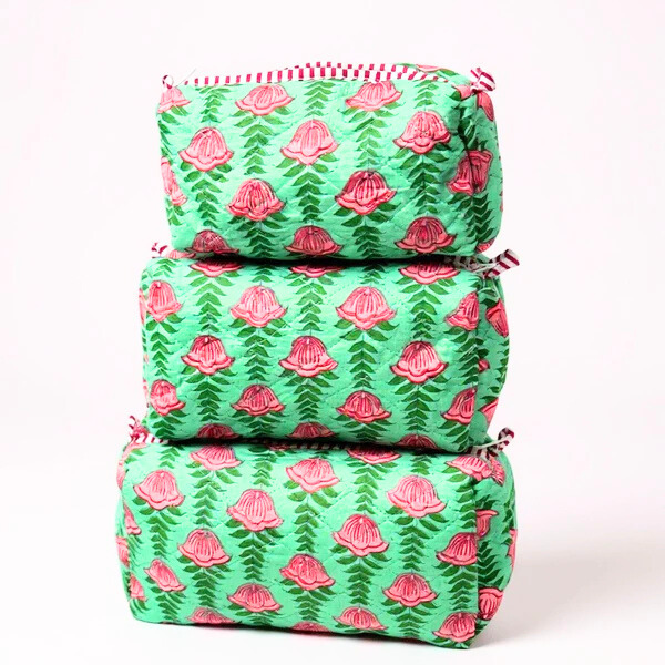 Stack of green fabric bags with pink floral patterns on a white background
