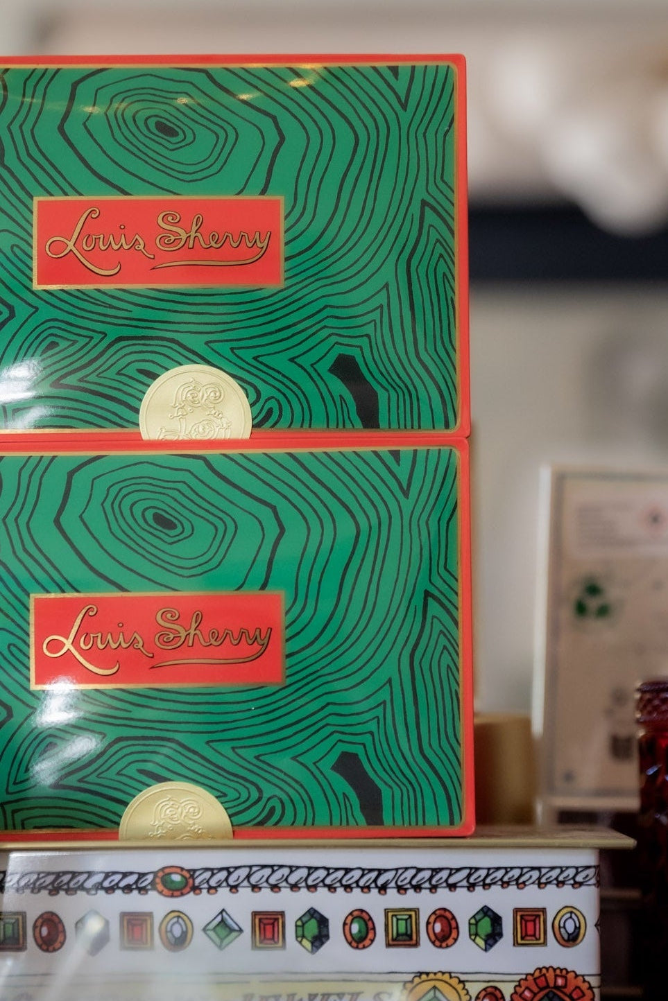 Green gift boxes with red labels, earrings, and candles on a table.